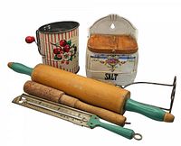 Photo showing the vintage hand-crank flour sifter, ceramic salt box, two wooden rolling pins, and metal kitchen thermometer arranged together.