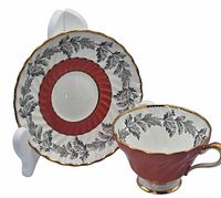 Porcelain cup and saucer displayed on stand showing side and top views, highlighting design and gold accents