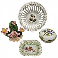 Four porcelain items including cactus, pierced round bowl with bird, rectangular pierced basket with cherubs, and covered trinket box with floral design.