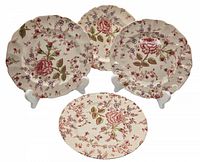 Four Johnson Bros decorative sandwich plates arranged on stands, showing floral pattern and scalloped edges.