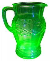 Green uranium glass pitcher glowing bright green under UV light showing vibrant uranium glass fluorescence.