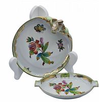 Two hand-painted porcelain dishes displayed, one oval and one triangular with gold accents and detailed hand-painted florals and butterflies.