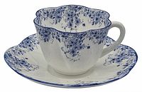 Cup and saucer set photographed together showing blue floral pattern and scalloped edges.