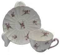 Cup and saucer set showing both pieces with rose spray decoration and scalloped edges.