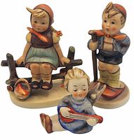 Front view of three vintage Goebel figurines: girl on fence, boy standing with stick, child sitting with instrument