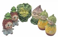 Three sets of vintage ceramic salt and pepper shakers displayed: strawberry-shaped, cabbage head, and yellow fruit/vegetable characters.