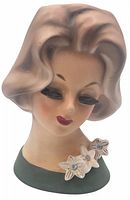 Front view showing detailed face and floral decoration on green base.