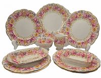 All eleven pieces arranged showing floral designs and gold accents. Plates, dishes and creamer in view.
