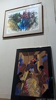 Both framed paintings hung on wall, one above the other