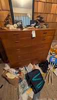 Front view of six-drawer wooden dresser with tags and miscellaneous items on top