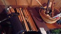 Assortment of wooden drumsticks and mallets with soft heads, plus storage items on a wooden surface.