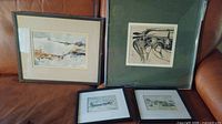 Four framed art pieces arranged on leather surface