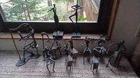 Overview of metal figurines arranged on a window ledge including musicians and a dancer showing shapes and posture