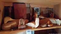 Wide shelf view showing a collection of wooden animal sculptures including ducks and a dolphin, along with a pencil holder.