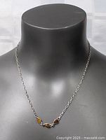 Full view of the sterling silver chain necklace displayed on a black bust showing chain length and three amber stones.