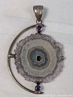 Full view of sterling silver amethyst geode pendant on white fabric background