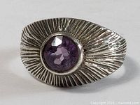 Front view of sterling silver amethyst ring showing textured carved design and center purple faceted stone