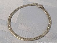 Sterling silver bracelet laid flat on grey fabric background showing full length and clasp
