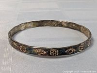 Full view of vintage sterling silver carved bangle bracelet with visible dark patina and floral leaf relief design around circumference.