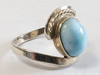 Close up side view of the sterling silver ring showing the carved twisted rope detail and the smooth blue oval stone cabochon.