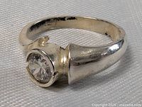 Close-up photo of front and side profile of sterling silver ring with clear round crystal, showing the crystal setting and band detail.