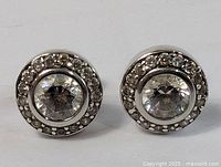 Front-on view showing both round sterling silver stud earrings with central and surrounding clear stones.