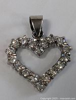 Front close-up of the sterling silver heart pendant showing sparkling clear stones and polished metal finish.