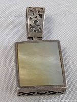 Front close-up of sterling silver pendant with square mother of pearl inlay and decorative bail.