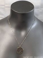 Front view of the sterling silver necklace showing the oval filigree pendant and beaded chain on a display bust.