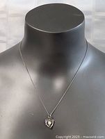 Front view of necklace displayed on a black mannequin highlighting the heart pendant with pearl.