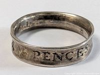 Close-up of the ring showing engraved inscription 'PENCES' and part of other text.