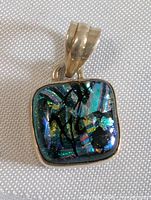 Front view of square colorful pendant with iridescent glass and silver frame
