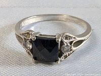 Front view of sterling silver ring showing square black faceted stone and clear accent stones on sides.