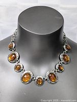 Front view of vintage costume necklace showcasing amber oval cabochons set in silver-tone metal frames on a black mannequin bust.