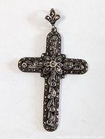 Close-up of vintage silver jeweled cross pendant showing filigree and marcasite details