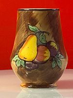 Front view of the vase showing colorful hand painted pear, plums or peaches, and grapes on a brown swirled glazed background.