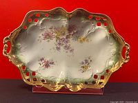 Full view of the rectangular serving bowl showing floral hand painting, gold trim, and pierced lattice design with handles.