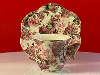 Photo of teacup and scalloped saucer showcasing floral chintz pattern and butterfly handle on cup