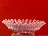 Side view of cranberry opalescent hobnail glass bowl showing ruffled edges and opalescent finish.