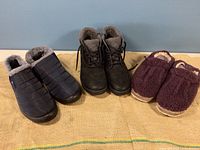 All three pairs of shoes together showing a navy nylon fleece-lined slip-on by BJ, black fleece-lined booties by Clarks, and purple fuzzy slippers by L.L. Bean.