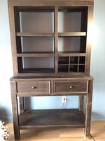 Front view of distressed black buffet hutch showing two drawers, open shelving and lower open shelf.
