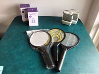 Three electric mosquito swatters and two Buzz B Gone electric bug zappers on table.