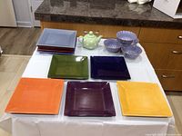 Set of colorful square plates, teapot, and soup bowls on table