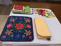 Full overview of all dish mats and pot holders arranged on a table showing variety of colors and patterns