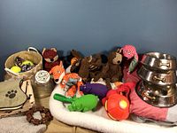 Full lot view showing metal dog bowls, plush dog toys, basket with balls, glass biscuit jar, dog pads, and collar.