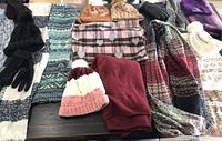 Full collection of hats, scarves, and gloves shown laid out on table, various patterns and colors visible including a large red scarf or throw.