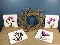 All four 12 x 12 flower canvas prints displayed with the lavender-like wreath against a blue wall, showing the set's overall look and size.