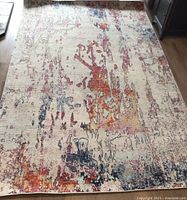 5x8 area rug with abstract contemporary multicolor design showing wear and pulls on the back.