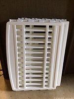 White plastic pet fencing panels stacked together showing slotted horizontal bars.