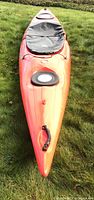 Front deck view of red kayak showing bow hatch, carry handle and deck bungee